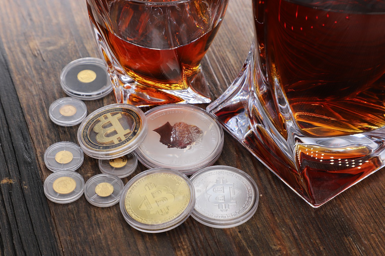 zdjęcie szklanek z alkoholem i monety z logiem różnych kryptowalut