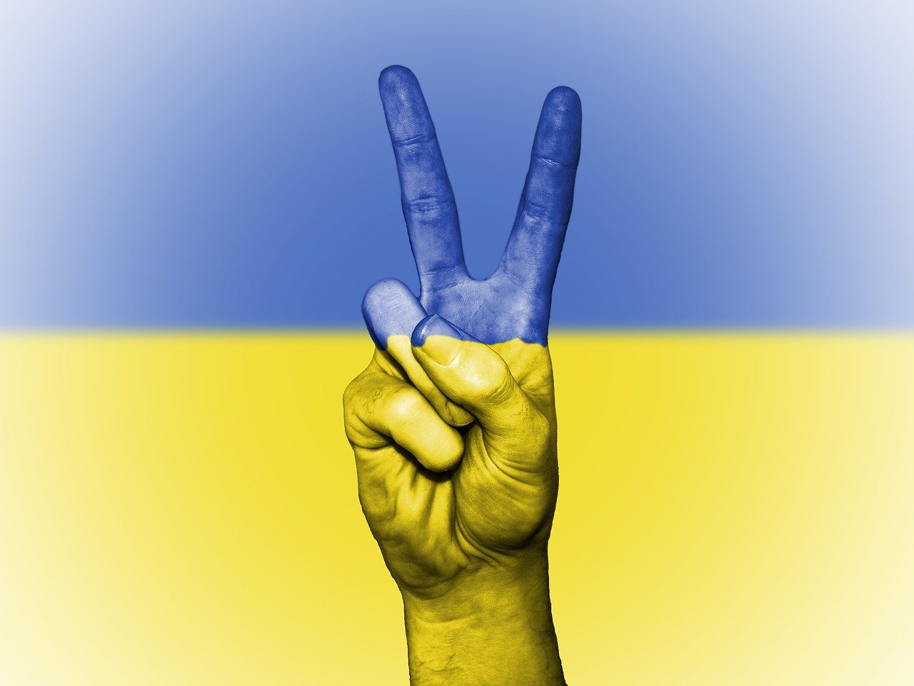 grafika przedstawiająca rękę w geście pokoju na tle flagi Ukrainy